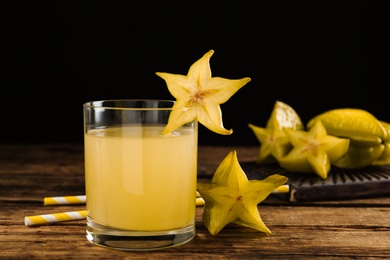 Delicious carambola juice in glass on wooden table