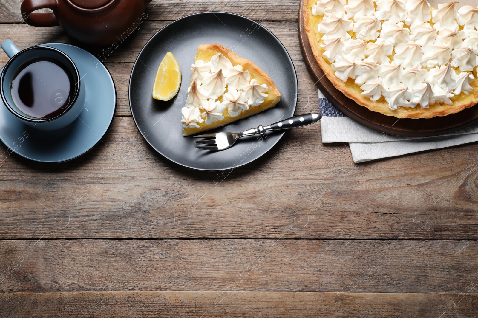 Photo of Cut delicious lemon meringue pie served on wooden table, flat lay. Space for text