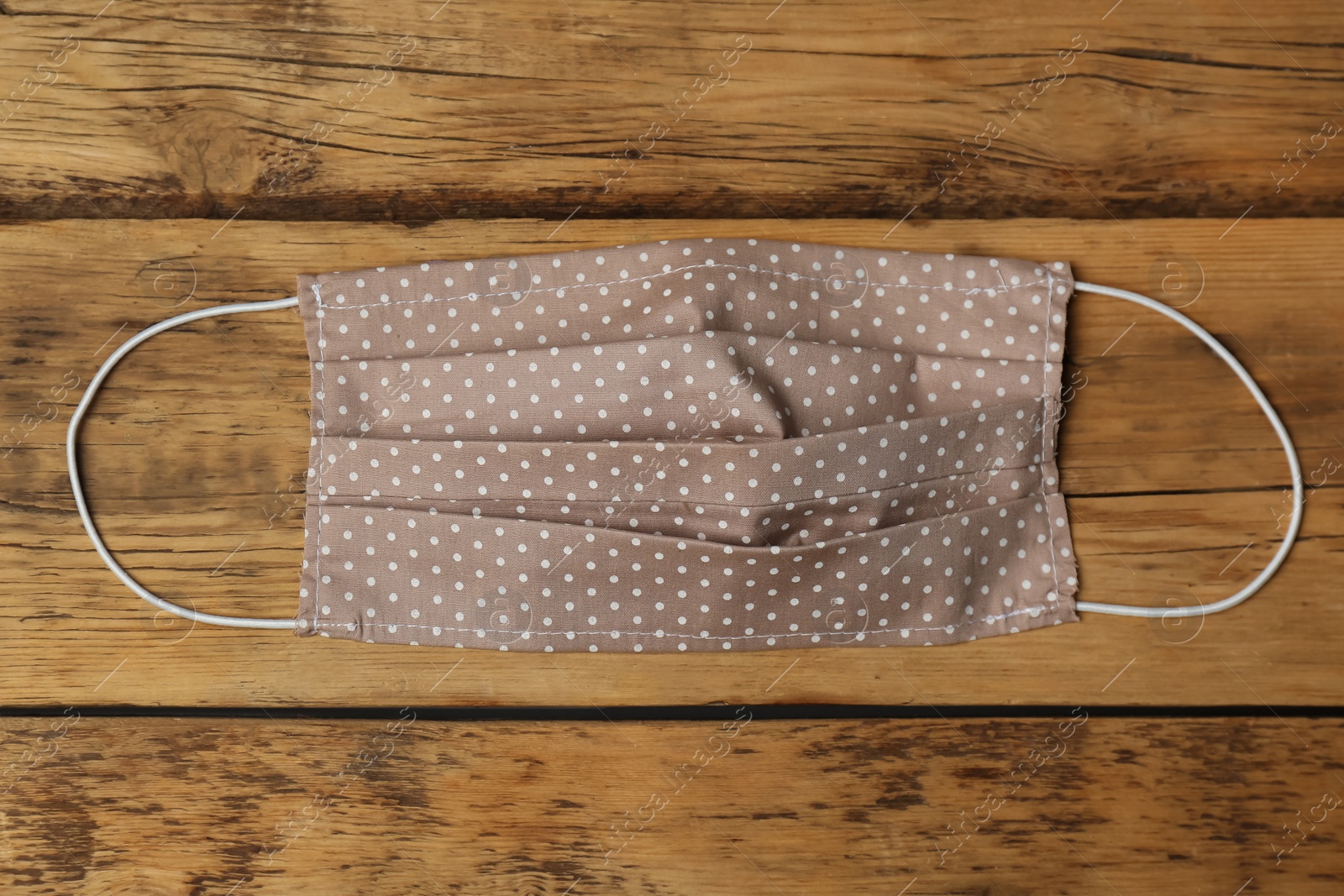 Photo of Homemade protective face mask on wooden table, top view