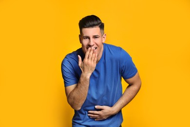 Photo of Handsome man laughing on yellow background. Funny joke