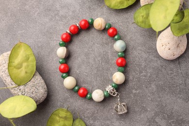 Photo of Beautiful bracelet with gemstones, leaves and stones on grey background, flat lay