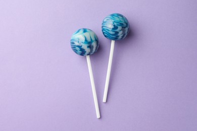 Photo of Tasty lollipops on violet background, flat lay