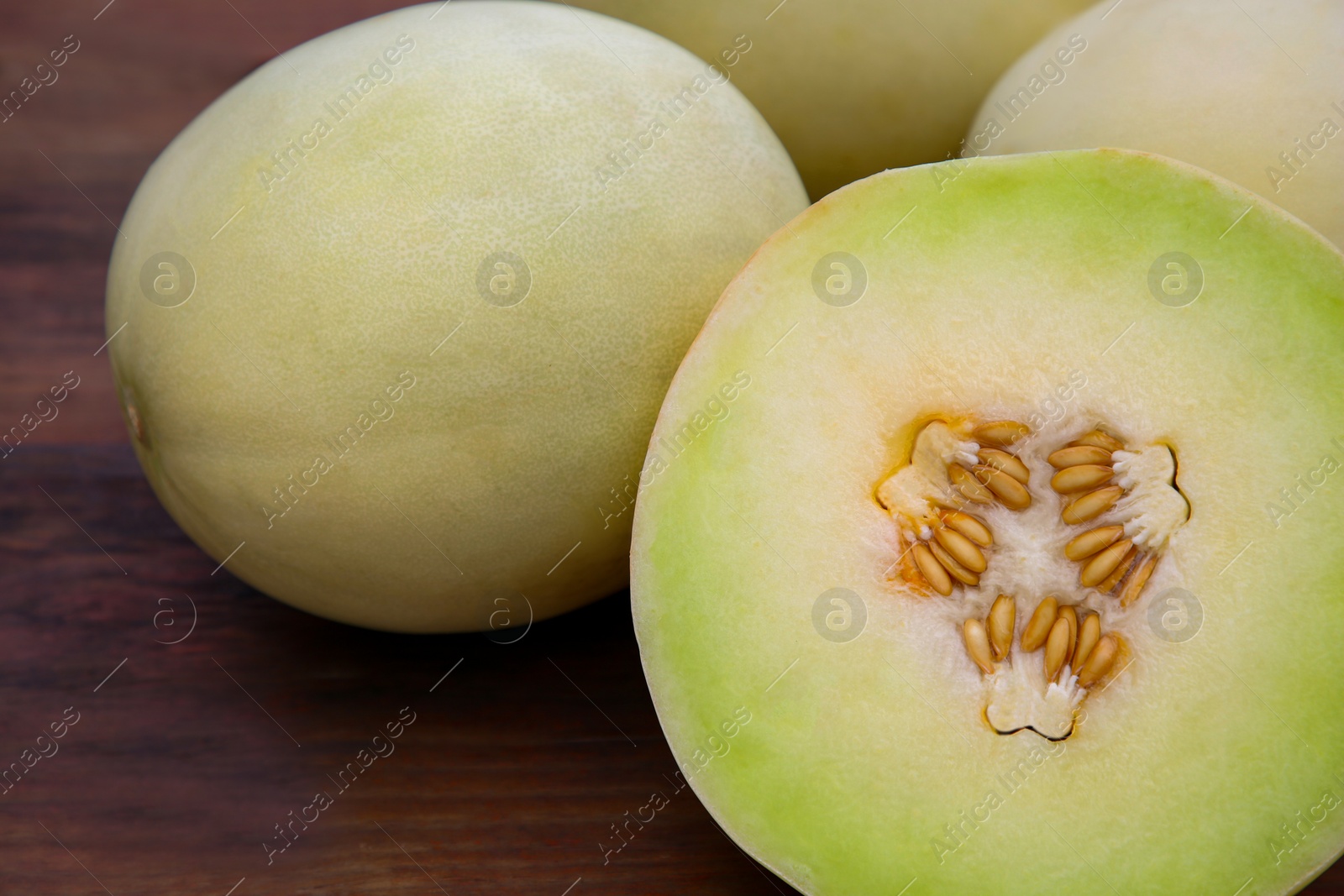 Photo of Whole and cut fresh ripe melons on wooden table, closeup