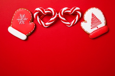 Photo of Christmas gingerbread cookies on red background, flat lay. Space for text