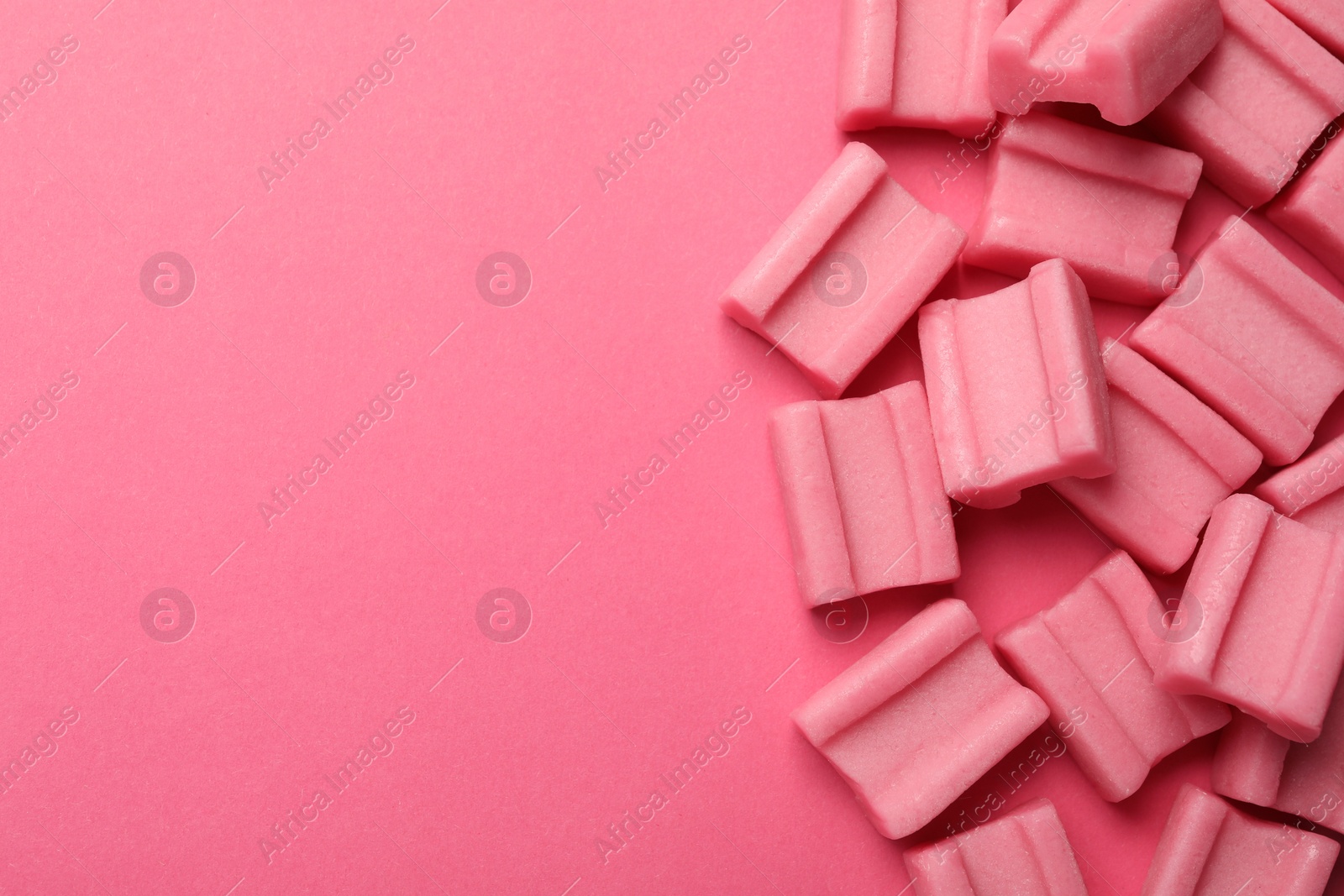 Photo of Tasty chewing gums on pink background, flat lay. Space for text