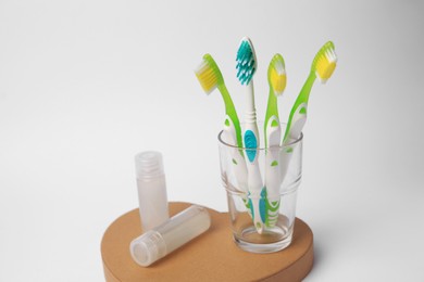 Colorful toothbrushes and cosmetic products on white background