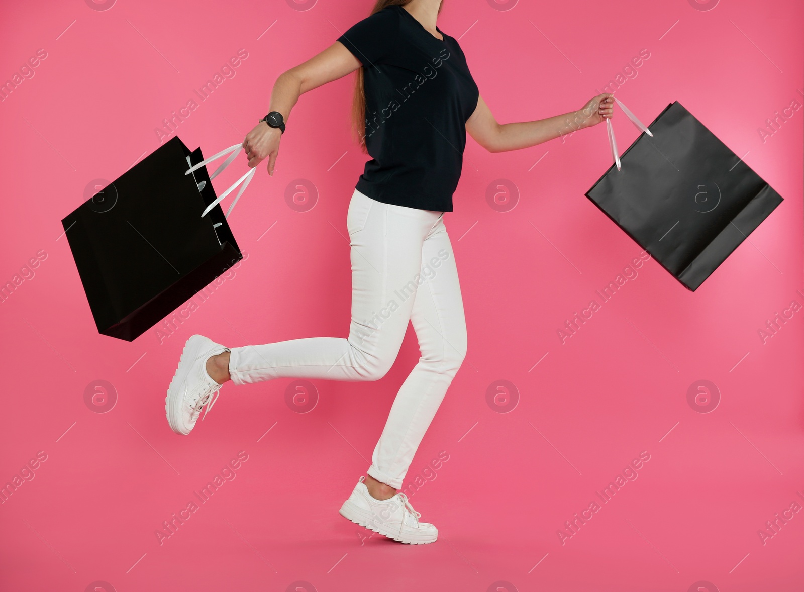 Photo of Woman running with paper shopping bags on color background. Mock up for design