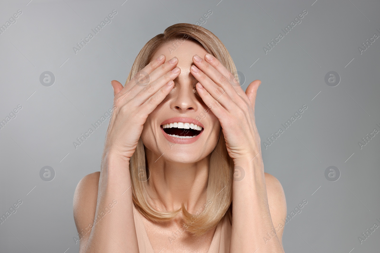 Image of Attractive woman with blonde hair closing her eyes on grey background