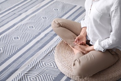 Woman meditating on wicker mat at home, closeup. Space for text