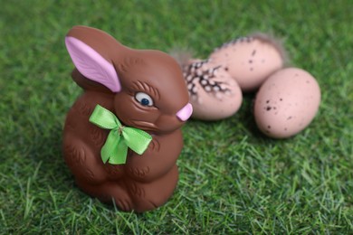 Easter celebration. Cute chocolate bunny and painted eggs on green grass