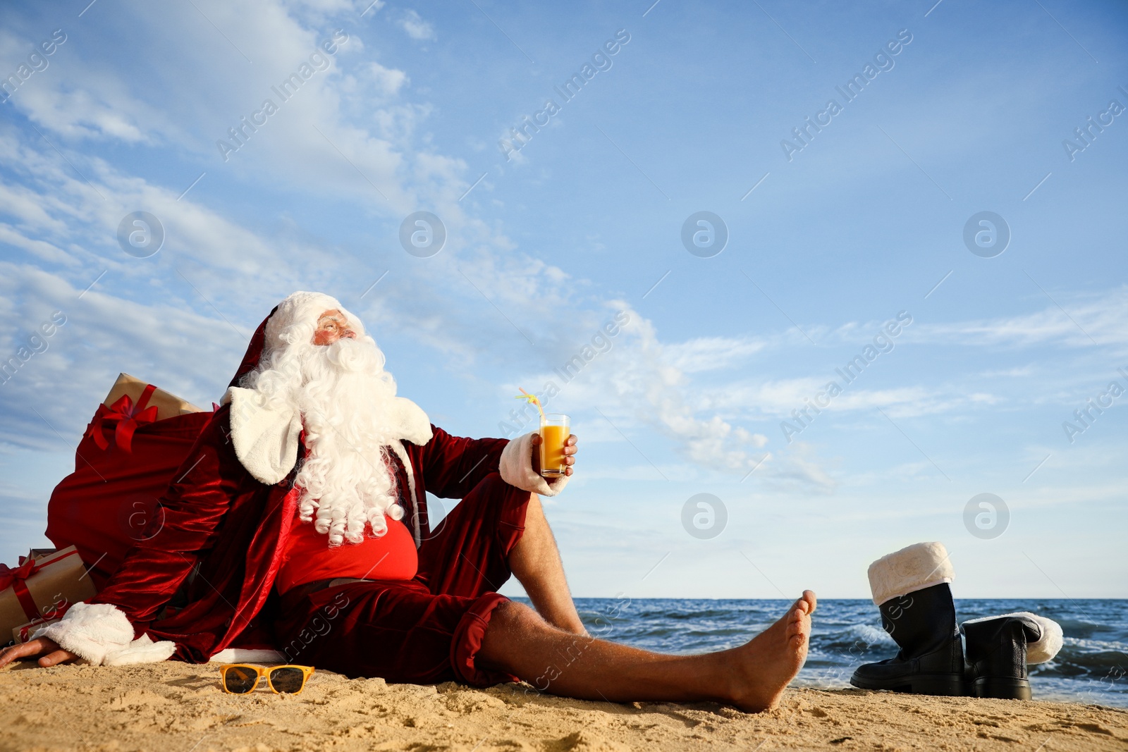 Photo of Santa Claus with cocktail relaxing on beach, space for text. Christmas vacation