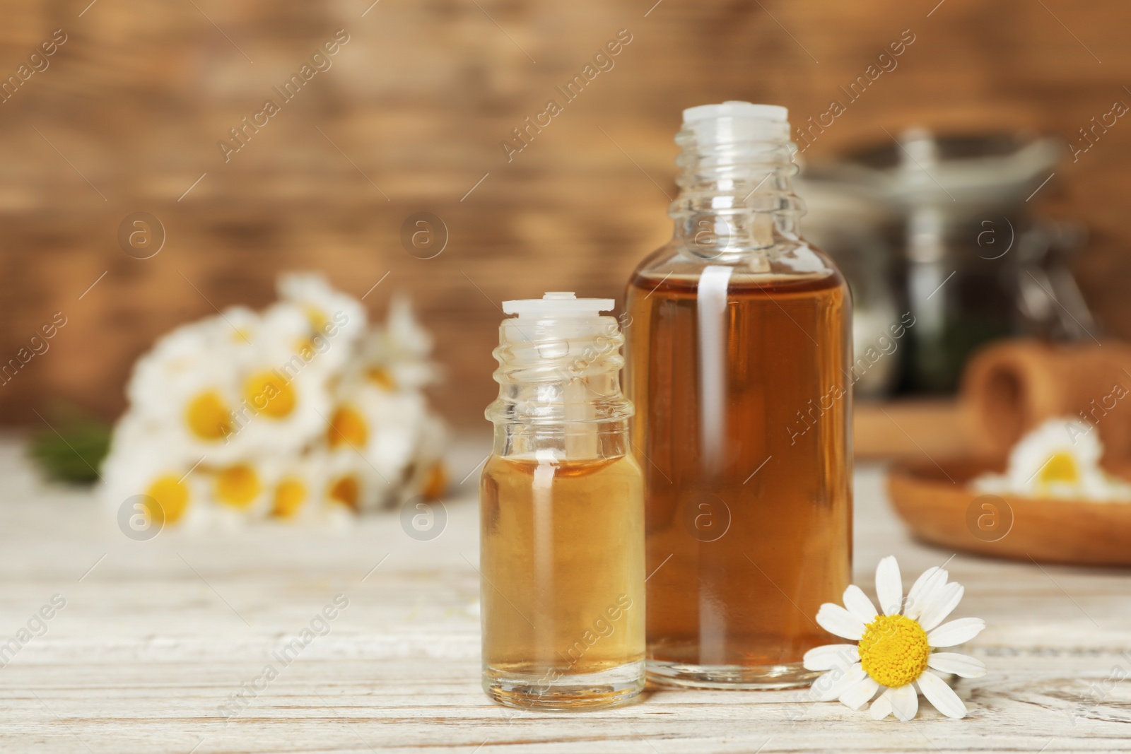 Photo of Composition with bottles of chamomile essential oil on table. Space for text