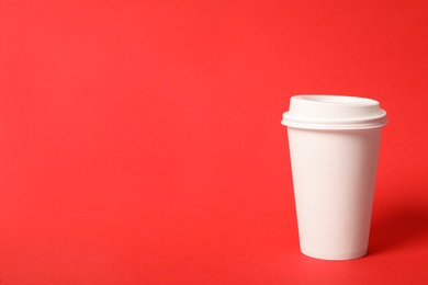 Photo of Takeaway paper coffee cup on red background. Space for text