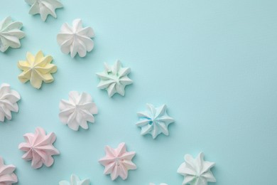 Photo of Delicious meringue cookies on light blue background, flat lay. Space for text