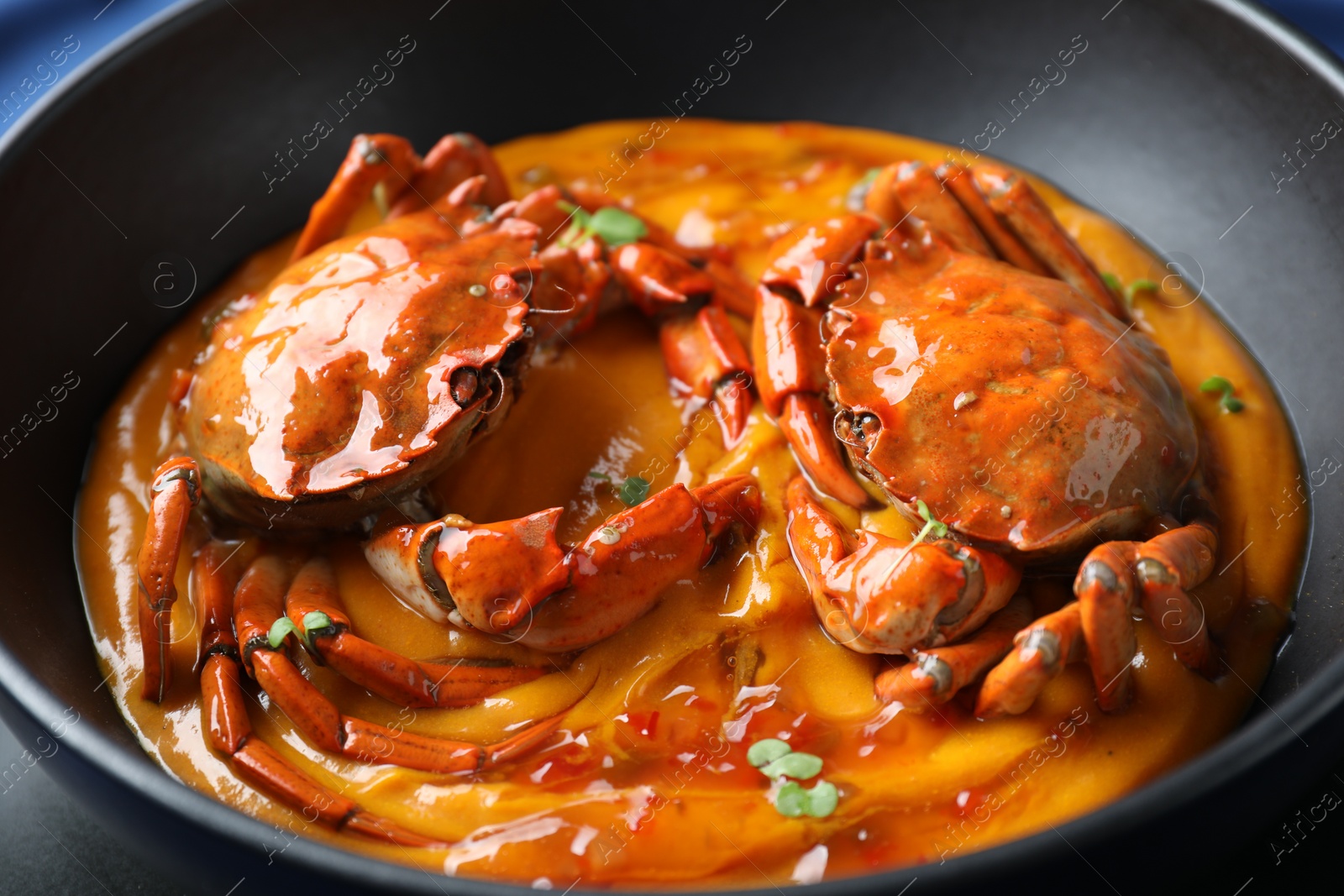 Photo of Delicious boiled crabs with sauce in bowl, closeup