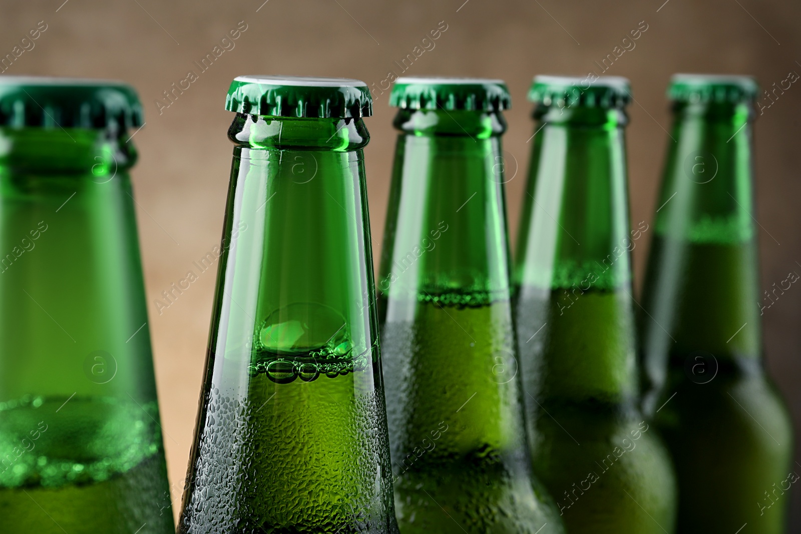 Photo of Many bottles of beer on light brown background, closeup