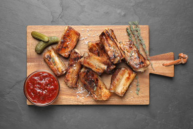 Delicious grilled ribs served on grey table, top view. Space for text