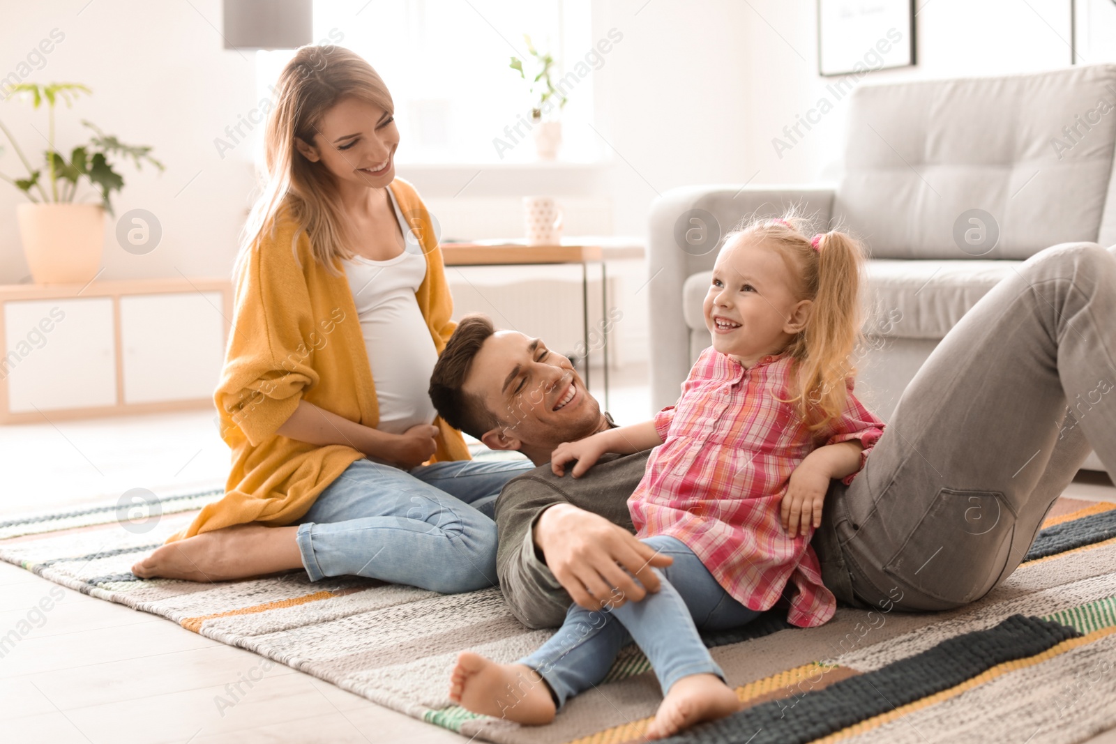 Photo of Young pregnant woman with her family at home