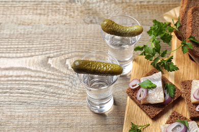 Photo of Cold Russian vodka with snacks on wooden table, above view