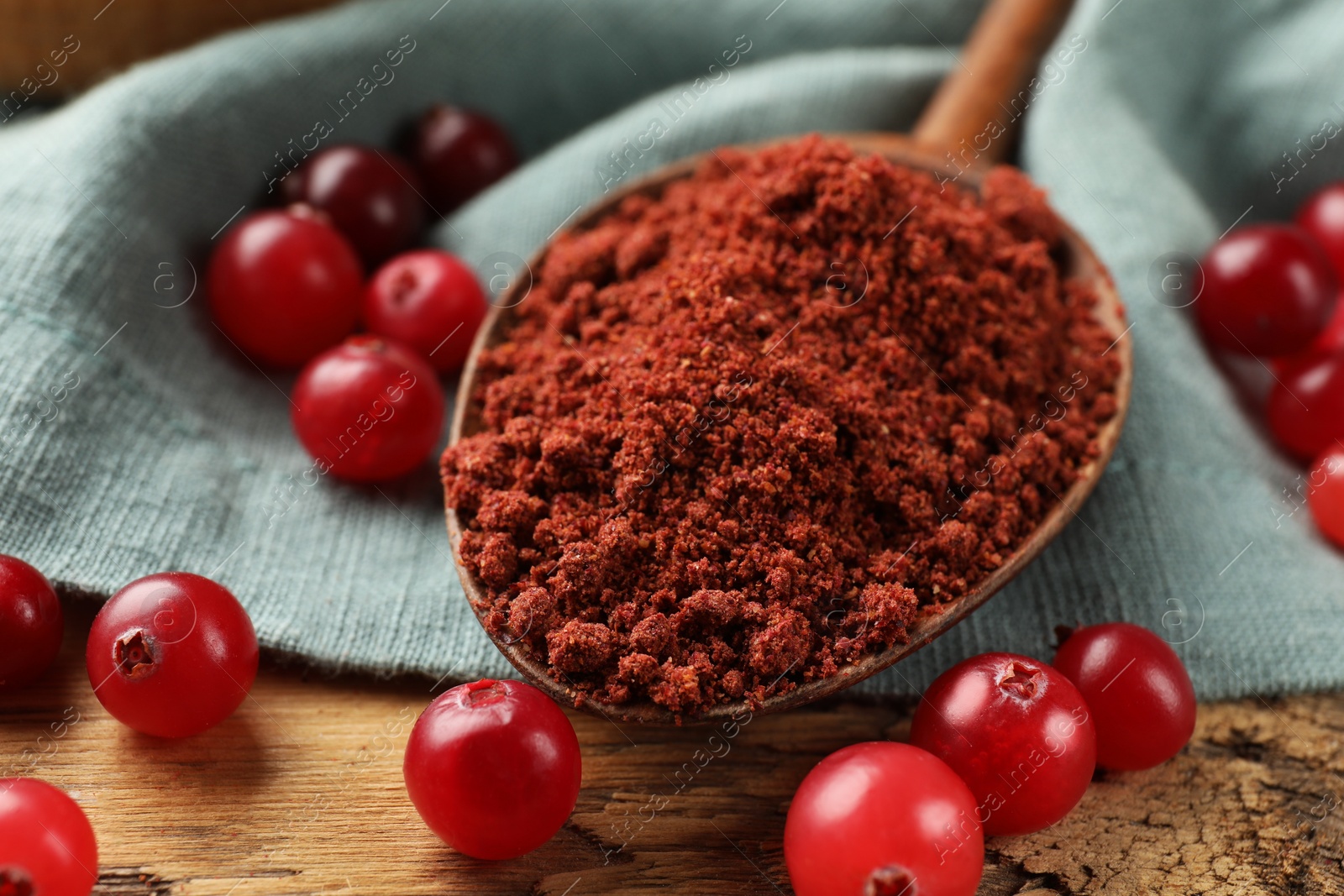 Photo of Spoon with cranberry powder and fresh berries on wooden table, closeup