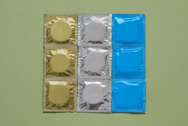 Condom packages on olive background, flat lay. Safe sex