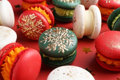 Photo of Beautifully decorated Christmas macarons and confetti on red background, closeup