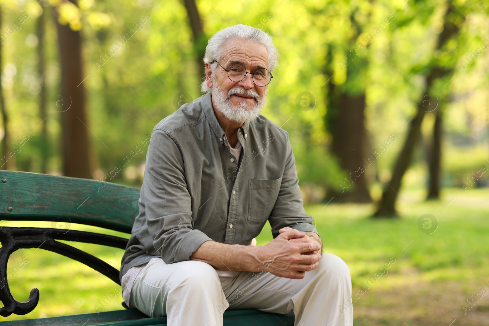 Photo of Portrait of happy grandpa with glasses on bench in park