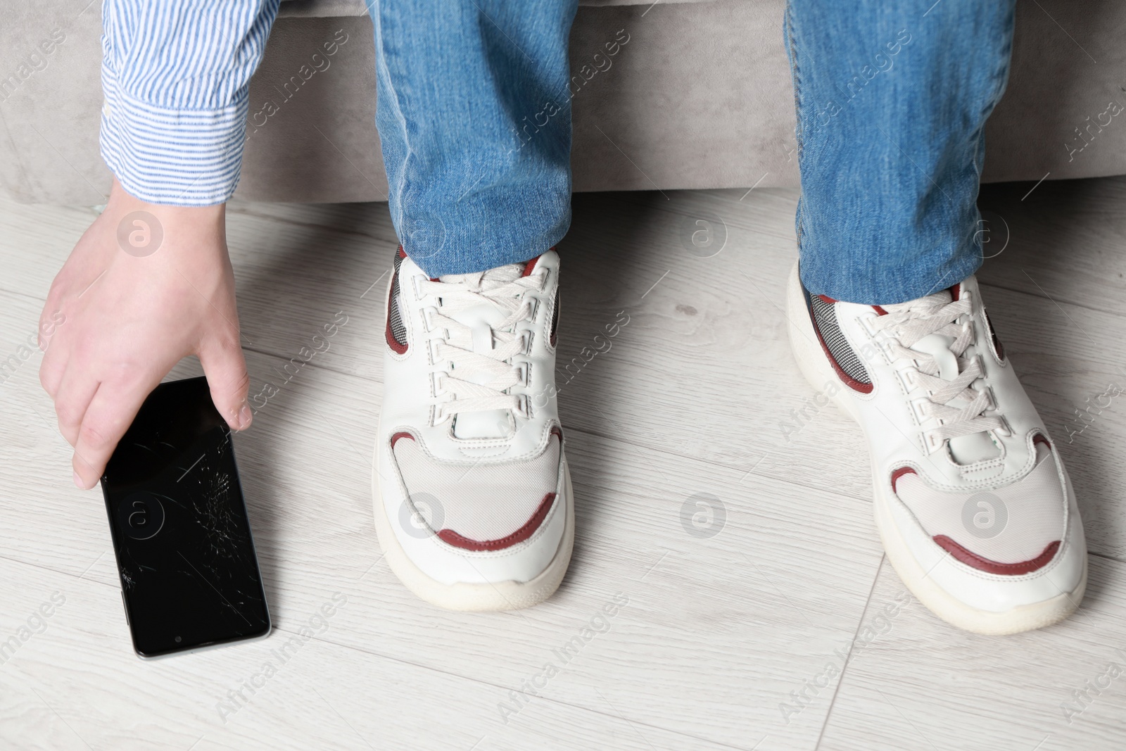 Photo of Man taking dropped smartphone from floor, closeup. Device repairing