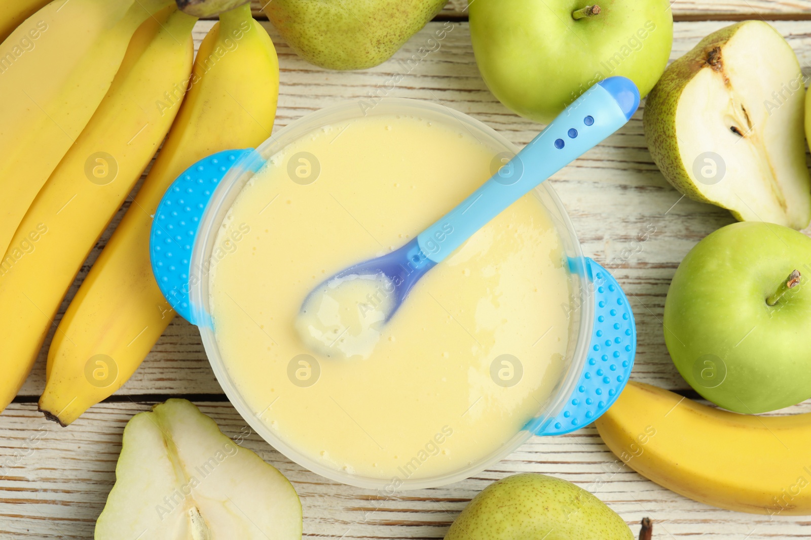 Photo of Baby food in bowl and fresh ingredients on white wooden table, flat lay