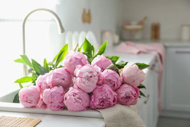 Photo of Bouquet of beautiful pink peonies in kitchen sink