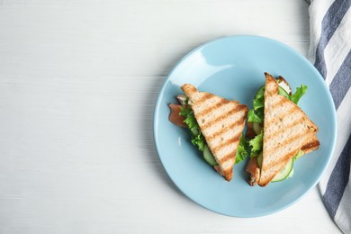 Photo of Blue plate with tasty sandwiches on white table, top view. Space for text