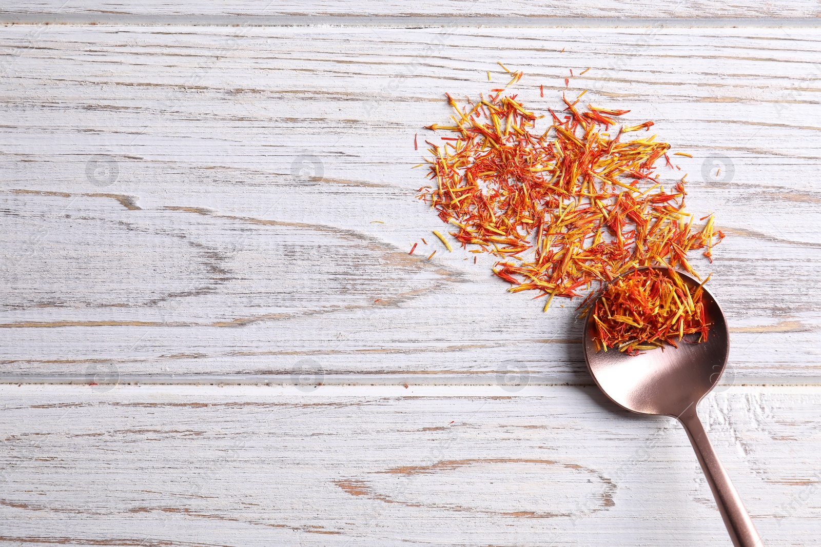 Photo of Aromatic saffron and spoon on wooden table, top view. Space for text