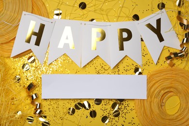 Flat lay composition with word HAPPY and party decor on yellow background. Space for text