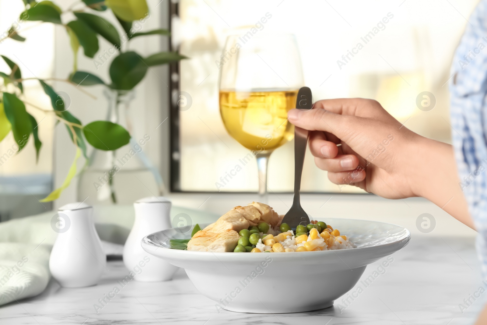 Photo of Woman eating tasty boiled rice with meat and vegetables at table, closeup