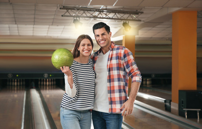 Happy couple with ball in bowling club