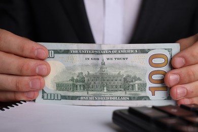 Money exchange. Man holding dollar banknotes at table, closeup