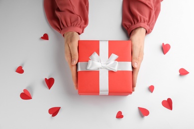 Photo of Woman holding gift box on white background, top view. Valentine's Day celebration