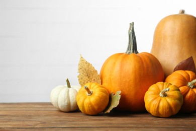 Thanksgiving day. Many different pumpkins and dry leaves on wooden table, space for text