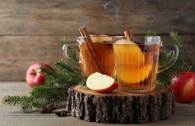 Photo of Hot mulled cider, ingredients and fir branches on wooden table