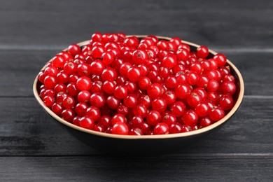 Ripe red currants in bowl on wooden rustic table