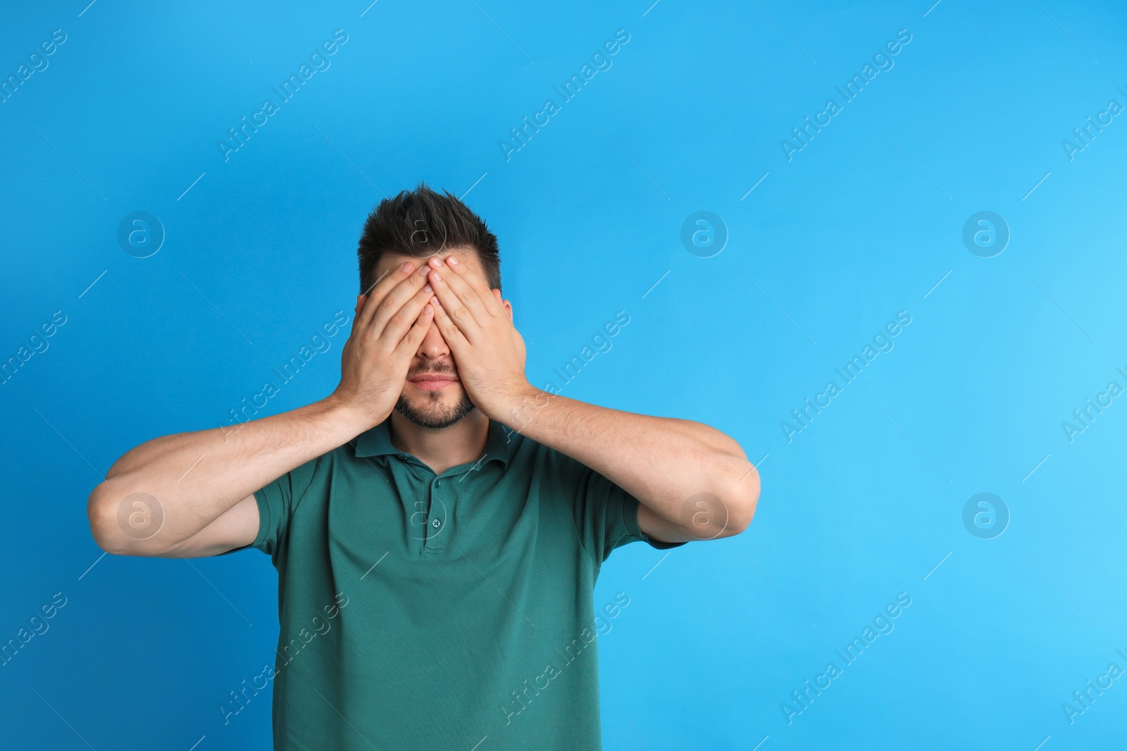 Photo of Man covering eyes while being blinded on blue background