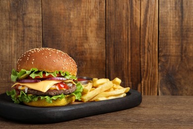 Delicious burger with beef patty and french fries on wooden table, space for text