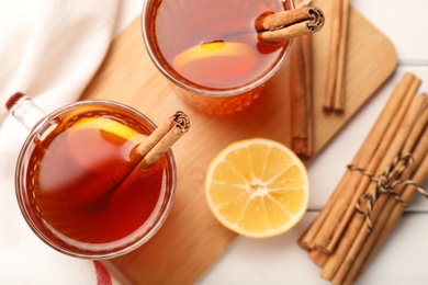 Photo of Delicious hot tea with cinnamon and lemon on white wooden table, flat lay