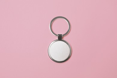 Photo of Metallic keychain with silver key ring on pale pink background, top view