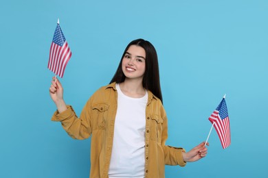 Photo of 4th of July - Independence Day of USA. Happy girl with American flags on light blue background