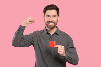 Emotional man holding condom on pink background. Safe sex