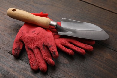 Pair of red gardening gloves and trowel on wooden table