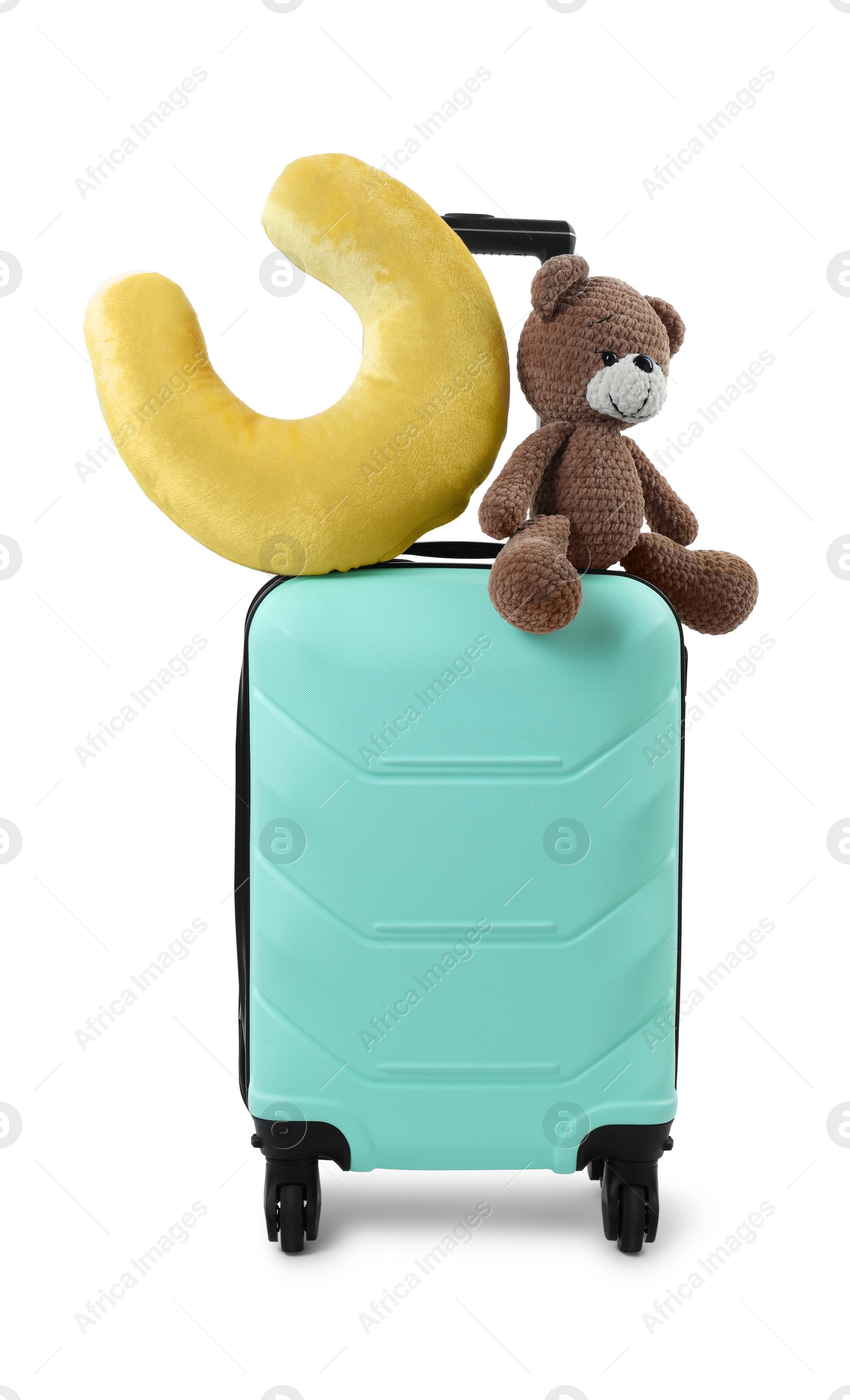 Photo of Soft travel pillow and toy bear on turquoise suitcase isolated on white