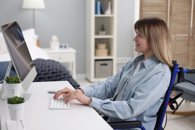 Photo of Woman in wheelchair using computer at table in home office