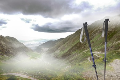 Image of Trekking poles and beautiful view of mountains on cloudy day. Space for text